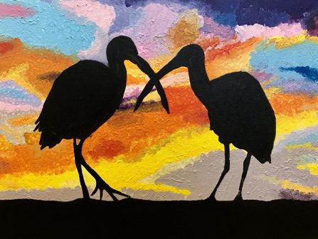 Two birds are silhouetted against a sunset.