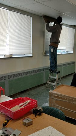 A man is working on a ceiling in an office.