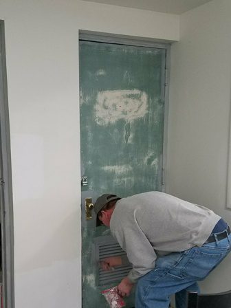 A man working on a door in a room.