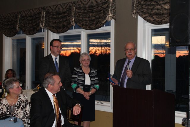 A group of people standing at a podium in front of a window.