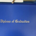 A blue book with the words diploma of graduation on it.