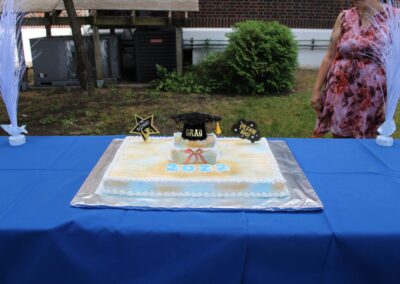 A woman is standing in front of a graduation cake.