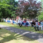 A group of people sitting in chairs in a park.