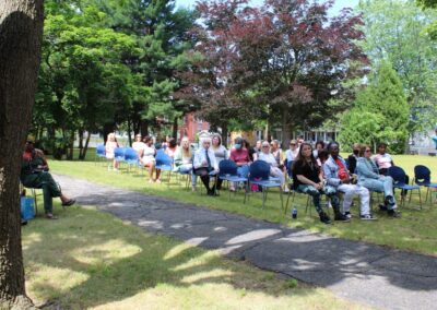 A group of people sitting in chairs in a park.