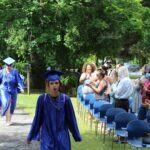 A group of people in graduation gowns walking down a path.