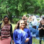Two women in graduation gowns walking down a path.