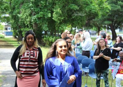 Two women in graduation gowns walking down a path.