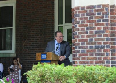 A man standing at a podium in front of a brick building.