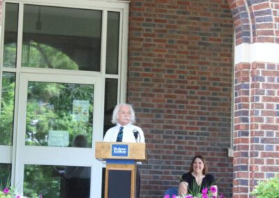 A woman standing at a podium in front of a brick building.