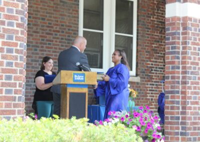 A woman is giving a speech at a podium in front of a brick building.