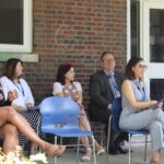A group of people sitting on chairs in front of a building.