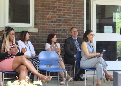 A group of people sitting on chairs in front of a building.