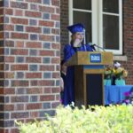 A woman in a graduation gown standing at a podium.