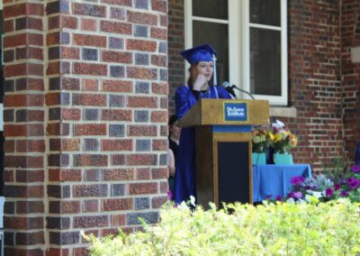 A woman in a graduation gown standing at a podium.