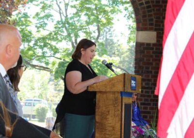 A woman speaks at a podium in front of an american flag.