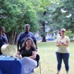 A group of people standing around a table in a park.