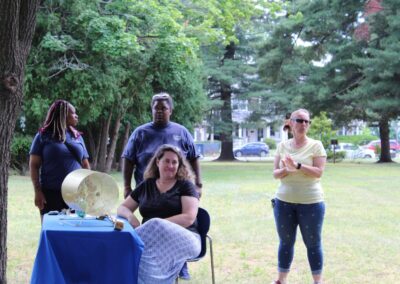 A group of people standing around a table in a park.