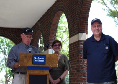 Three people standing at a podium in front of a brick wall.