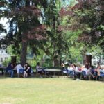 A group of people sitting at tables in a park.