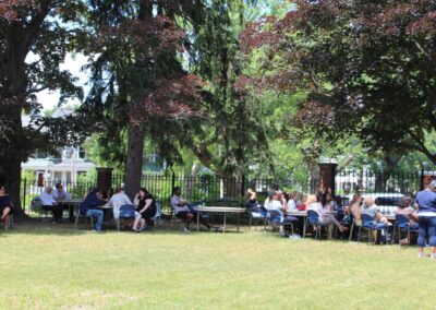 A group of people sitting at tables in a park.