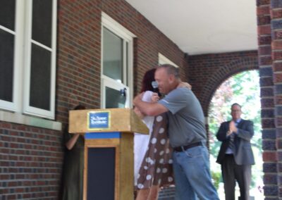 Two people hugging at a podium in front of a building.