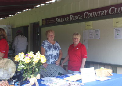 Two women standing in front of a table.