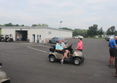 A group of people riding golf carts in a parking lot.