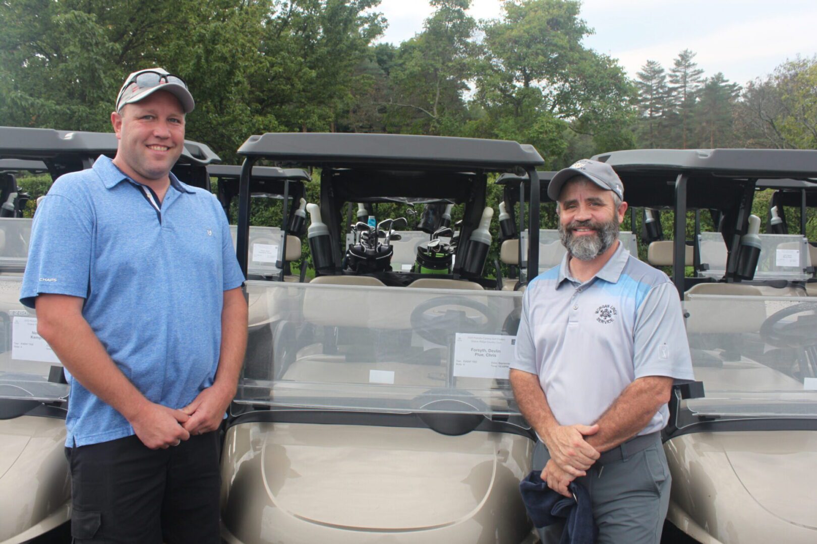 Two men standing next to a golf cart.