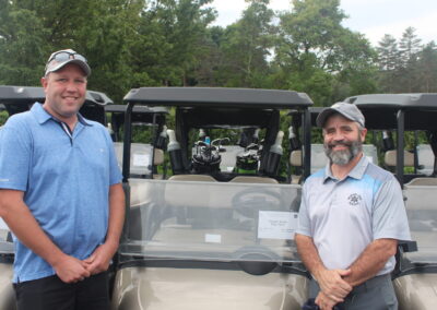 Two men standing in front of golf carts.