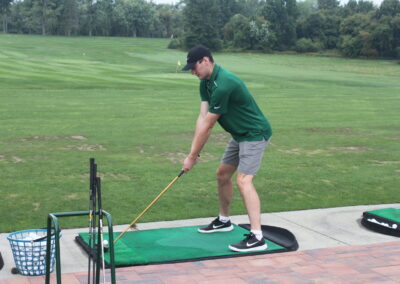 A man is hitting a golf ball on a golf putting green.