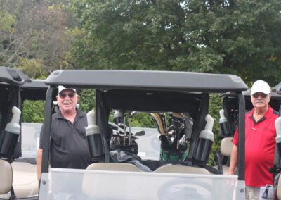 A group of men standing next to a golf cart.