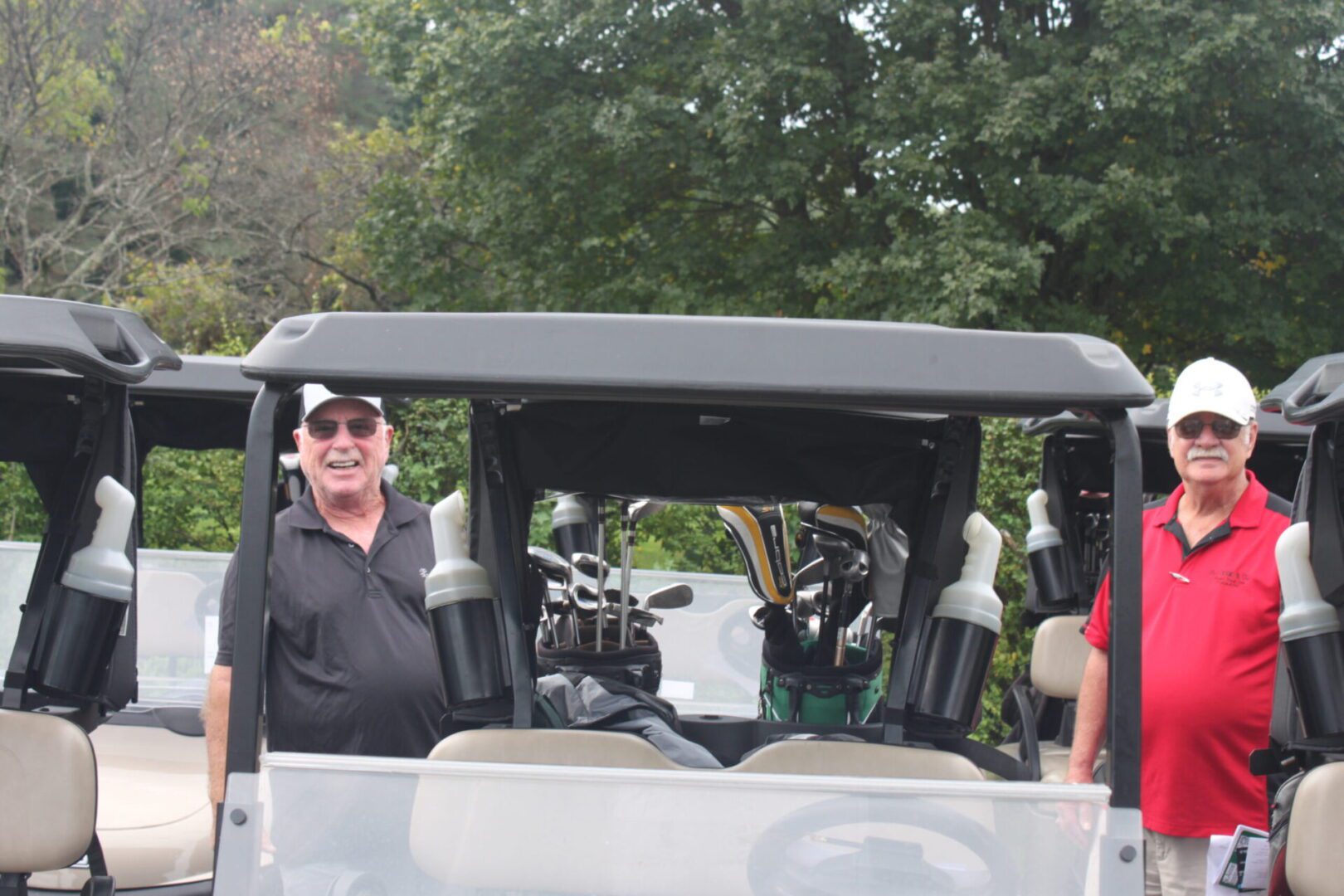 A group of men standing next to a golf cart.