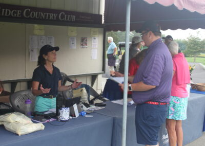 A group of people standing at a table at a golf tournament.