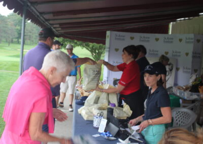 A group of people standing around a table at a golf tournament.