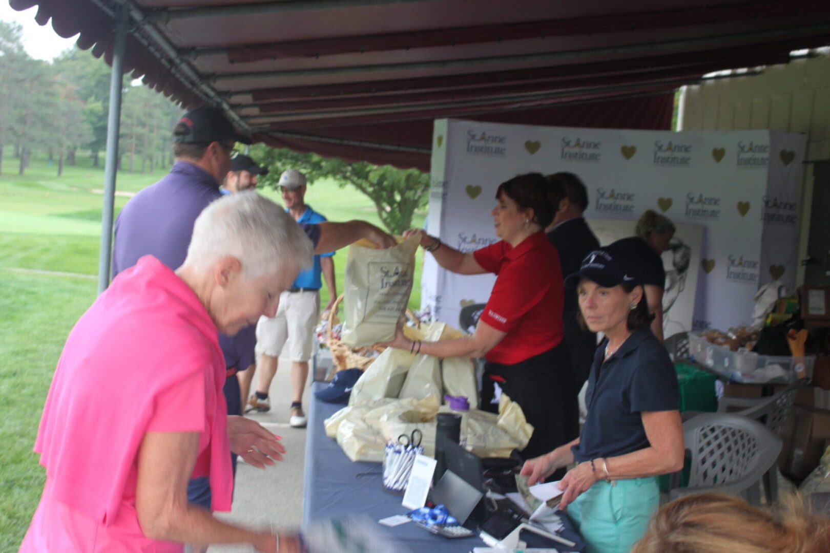 A group of people standing around a table at a golf tournament.
