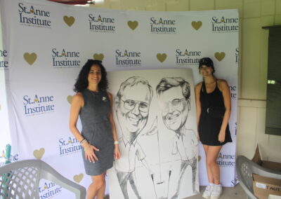 Two women posing for a photo with a caricature.