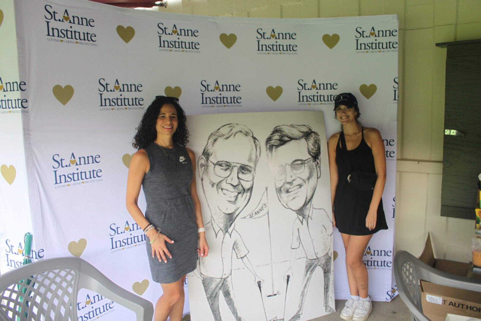 Two women posing for a photo with a caricature.