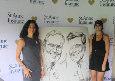 Two women posing in front of a caricature.