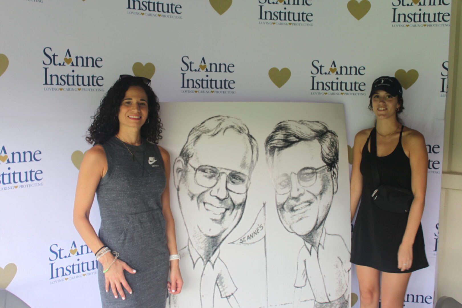 Two women posing in front of a caricature.