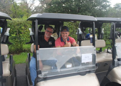 Two men in golf carts posing for a picture.