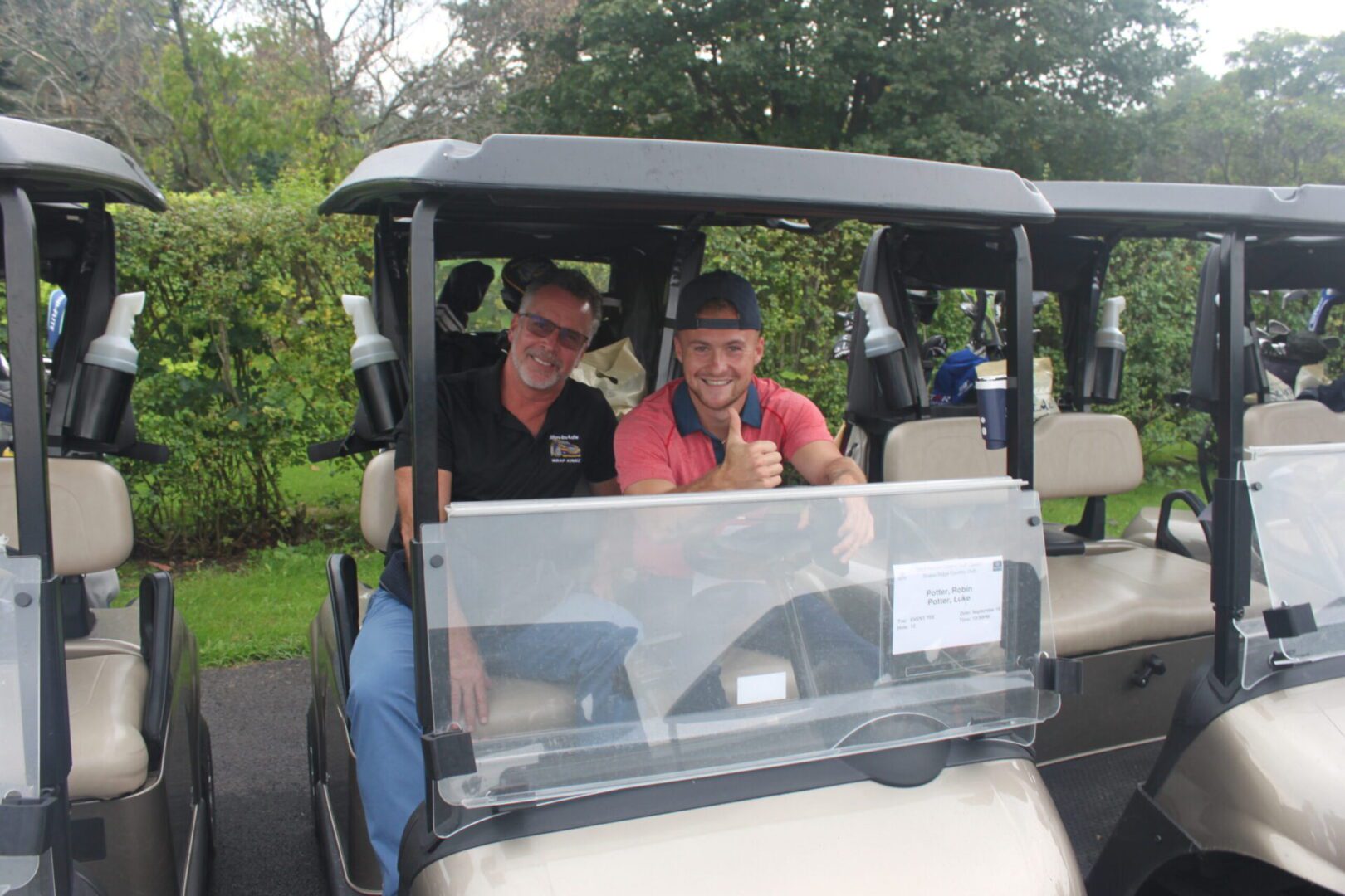 Two men in golf carts posing for a picture.
