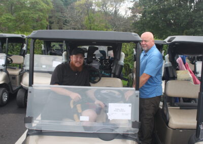 Two men standing next to a golf cart.