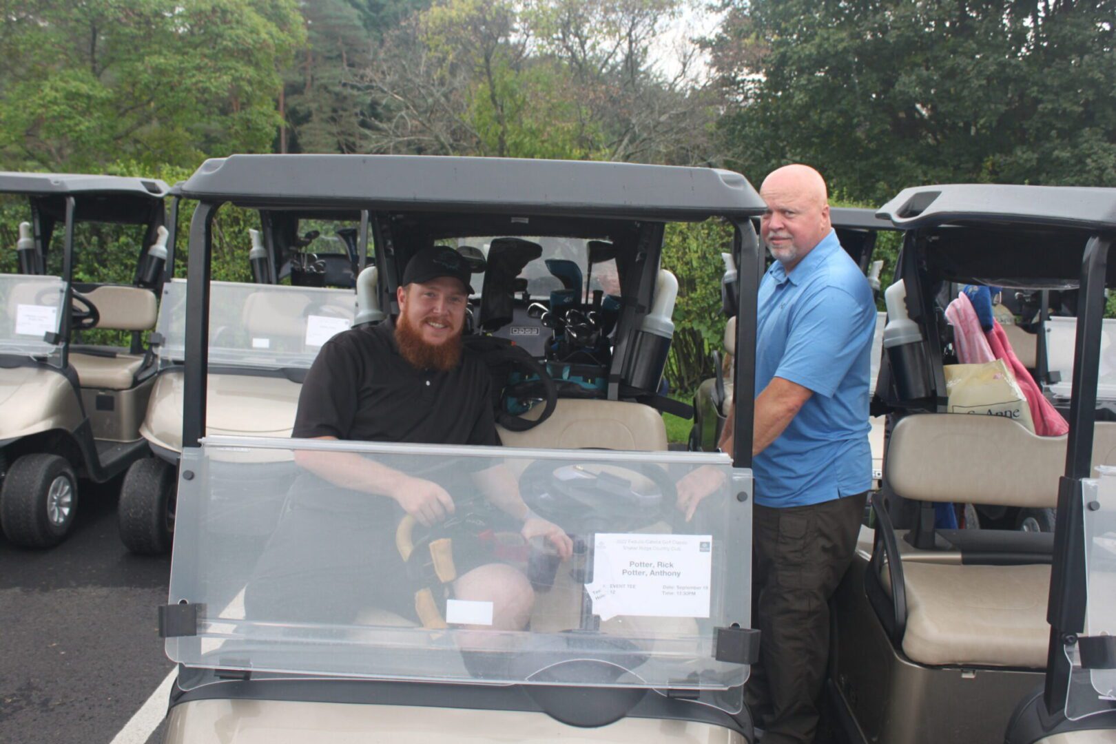 Two men standing next to a golf cart.