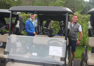 A group of men standing next to a golf cart.