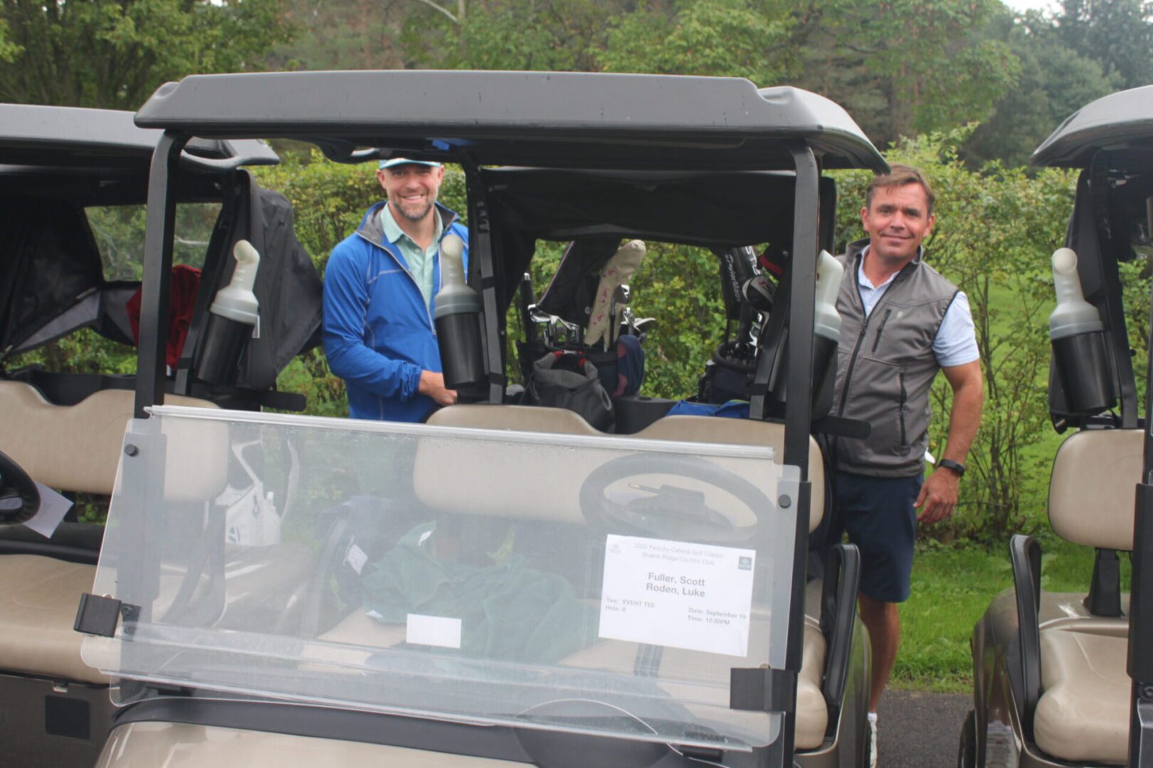 A group of men standing next to a golf cart.