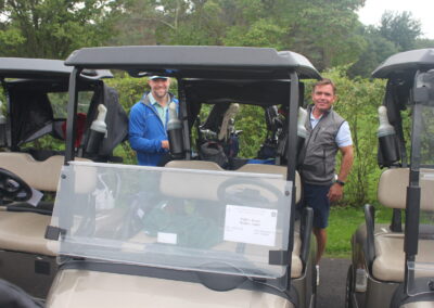 A group of men standing next to golf carts.