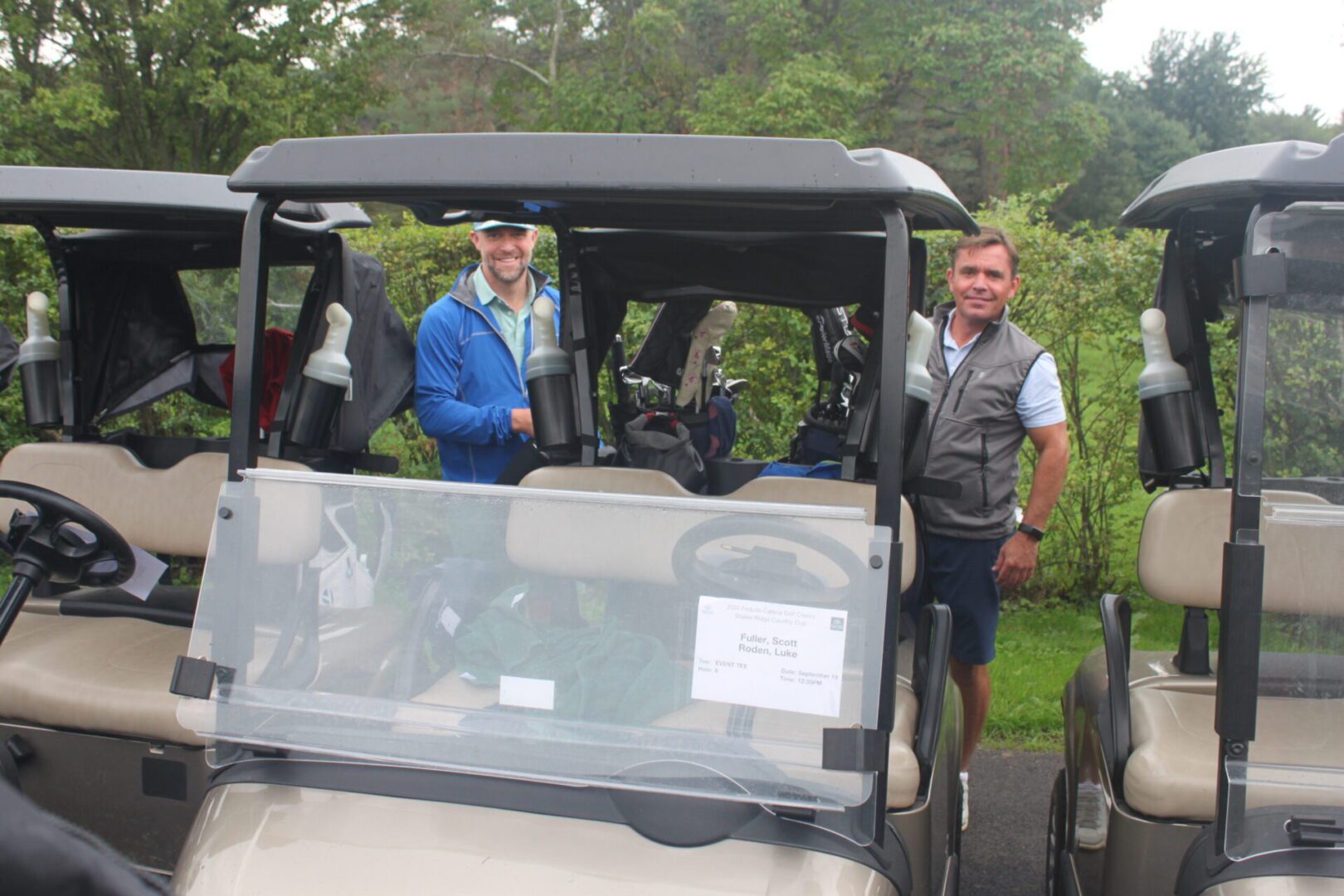 A group of men standing next to golf carts.