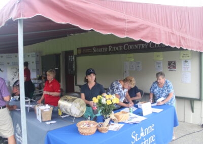 A group of people standing at a table under a tent.