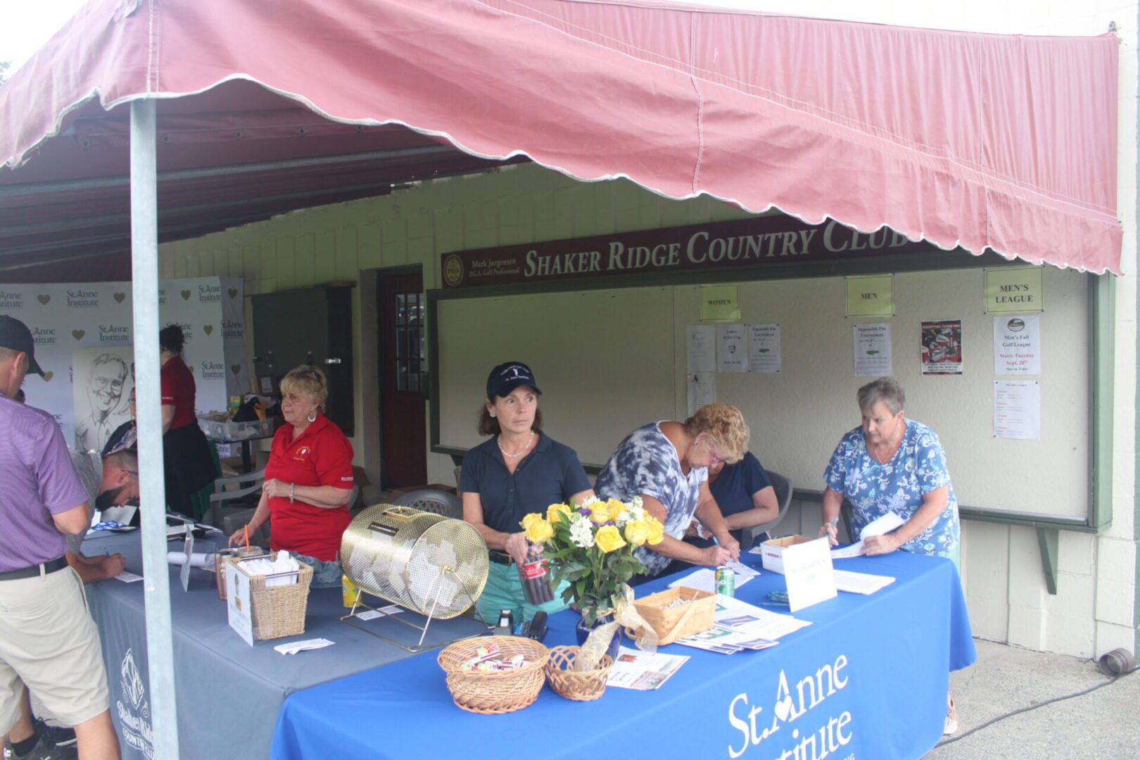 A group of people standing at a table under a tent.