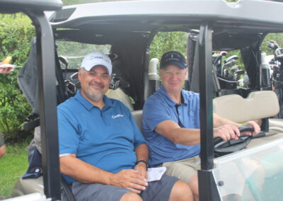 Two men sitting in the back of a golf cart.